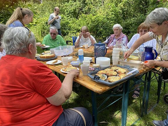Anwohnende des Quartiers genießen beim Nachbarschaftstreff „Sonnenblick“ ein gemeinsames Essen im Grünen.