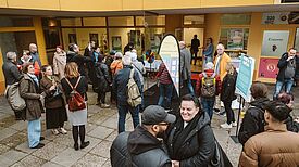 Viele Menschen stehen gemeinsam in einem offenen Raum.