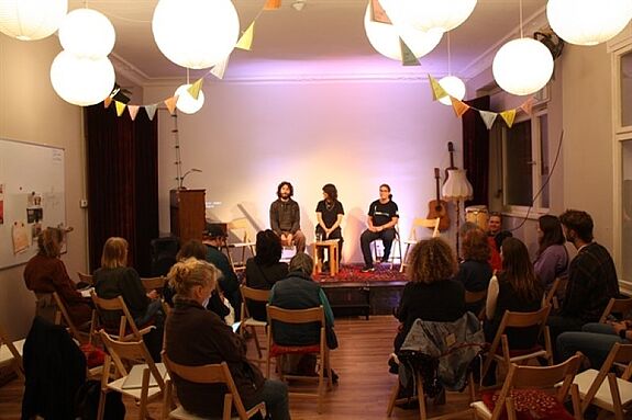 Teilnehmende sitzen im „Offenen Wohnzimmer“ während einer Diskussionsrunde des Stadtteilplenums Moabit.