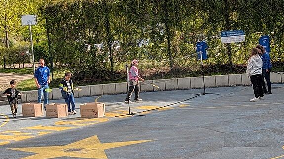 Mehrere Jugendliche spielen gemeinsam draußen Federball.
