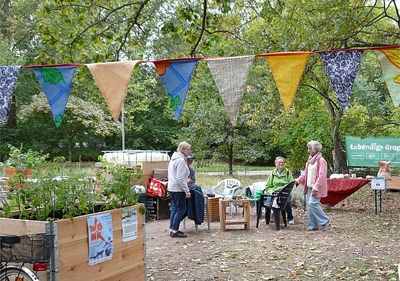 Mehrere Menschen sitzen auf Stühlen im Gemeinschaftsgarten. 