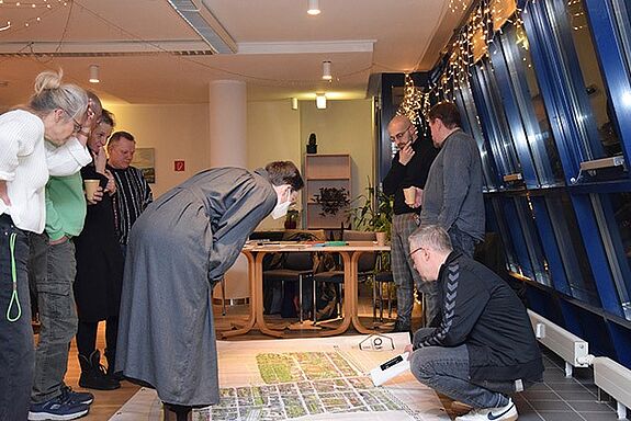 Eine Gruppe von Quartiersratsmitgliedern steht um eine Karte und bespricht Bauvorhaben im Kiez.