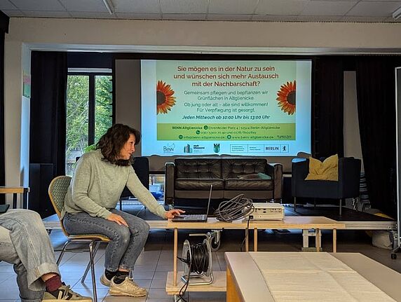 Ein Mitglied des BENN-Altglienicke-Teams sitzt vor einer Projektionsfläche und bereitet eine Präsentation über ehrenamtliches Gärtnern im Kosmosviertel vor.