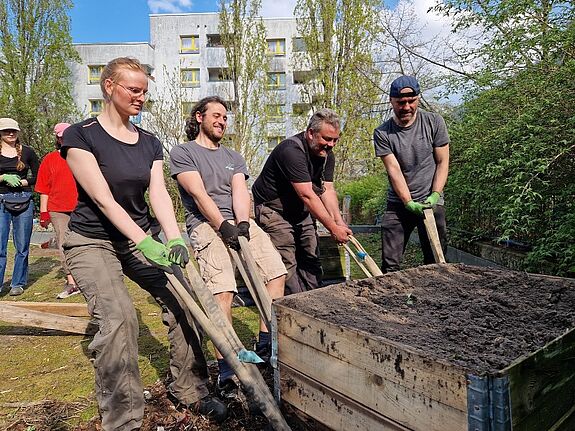 Zwei Mitglieder des Gartenteams bringen ein Schild am Eingang des Gemeinschaftsgartens im QM-Gebiet Rollbergsiedlung an.