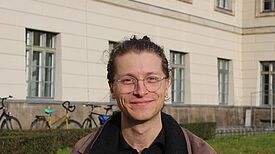 Lesepate Fabian Rehme steht vor einem Schulgebäude.