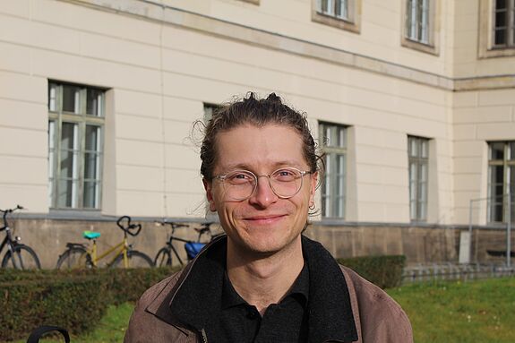 Lesepate Fabian Rehme steht vor einem Schulgebäude.