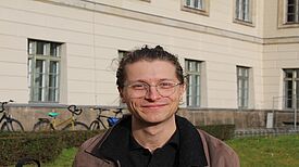 Lesepate Fabian Rehme steht vor einem Schulgebäude.