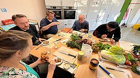 Fünf Teilnehmende kosten am Küchentisch das selbstgemachte Kimchi und fermentierte Gemüse.