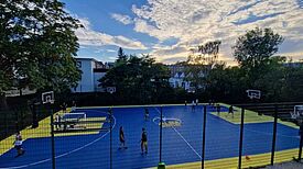Mädchen und junge Frauen spielen Basketball auf einem bunt markierten Platz an der Albert-Gutzmann-Schule.