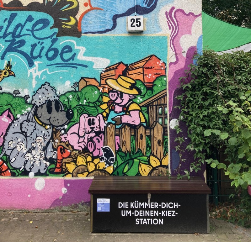 Eine Clean-Up-Box steht vor einer bunten Wandmalerei.