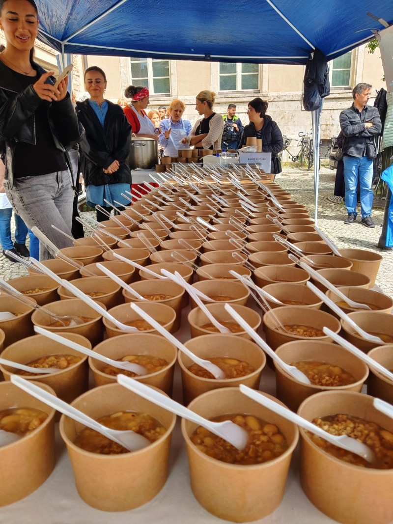 Becher mit der traditionellen Aschura-Süßspeise stehen in Reihen auf einem Tisch unter einem blauen Zelt