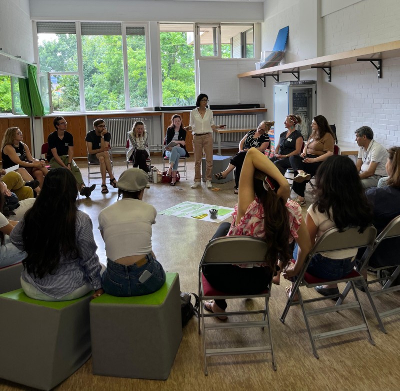 Teilnehmende sitzen in einem Stuhlkreis in einem hellen Raum und diskutieren beim Fachtag zur Gewaltprävention in der Gropiusstadt.