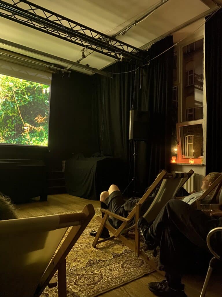 Innenraum mit Leinwand, Liegestühlen und Zuschauenden bei einer Filmvorführung im Kompostkino.