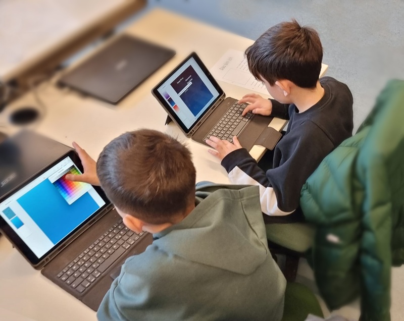 Zwei Jungs in einem Klassenzimmer sitzen an zwei iPads.